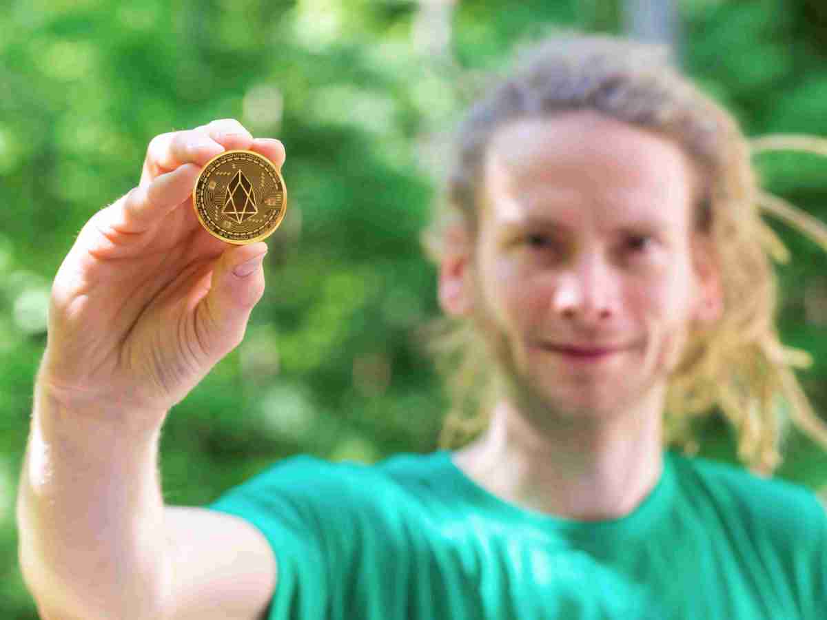 pessoa segurando uma moeda da eos criptomoeda