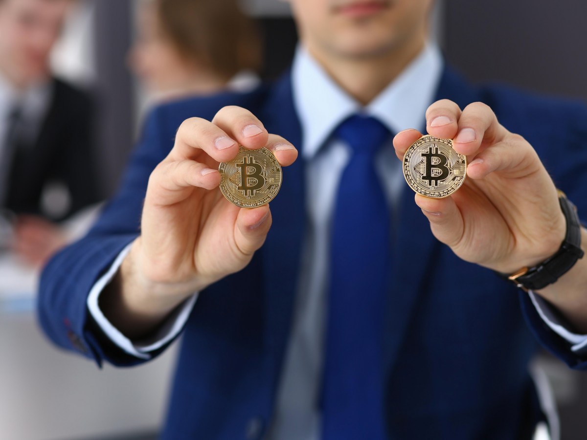 homem segurando duas moedas de bitcoin