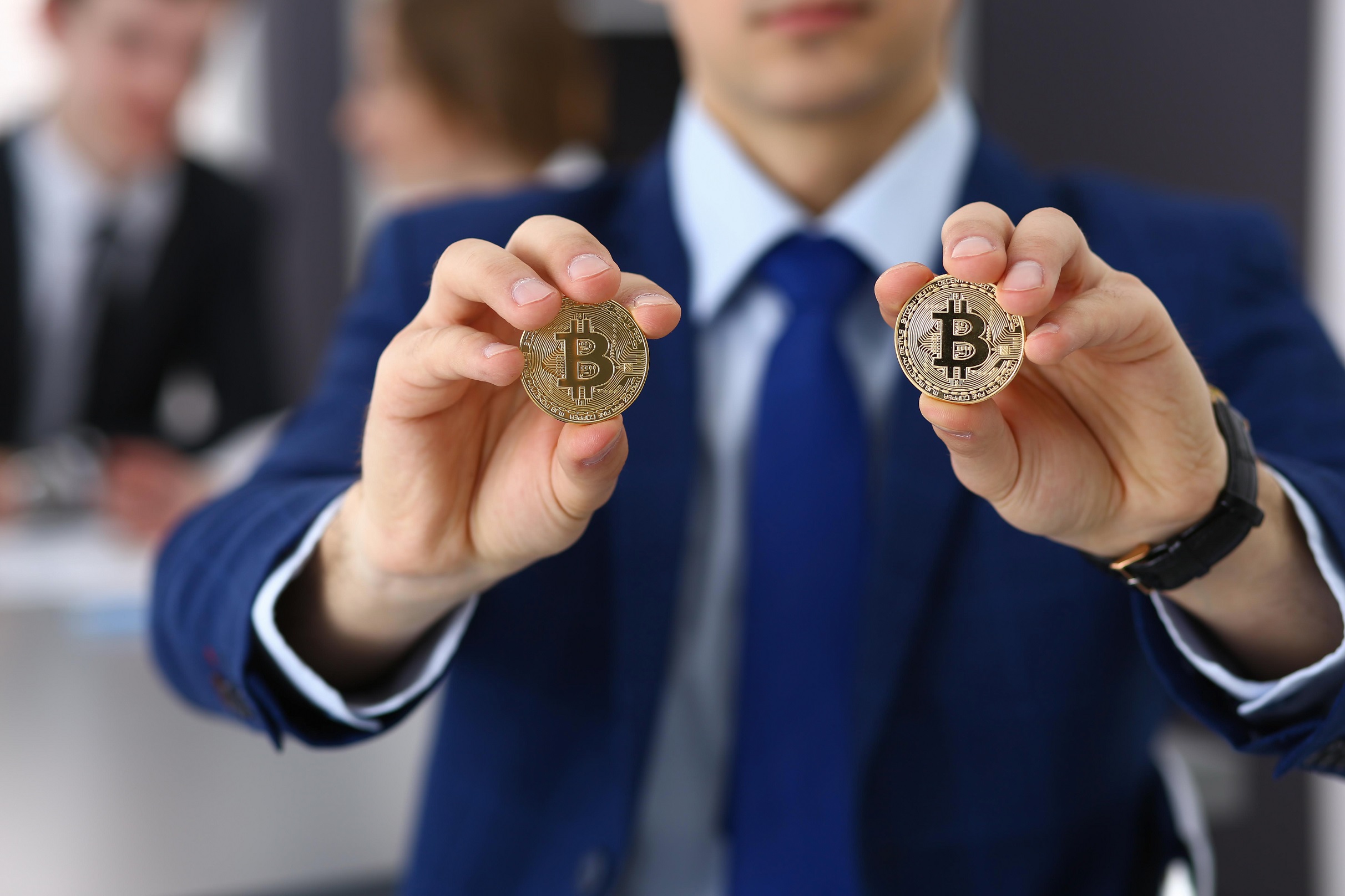 homem segurando duas moedas de bitcoin