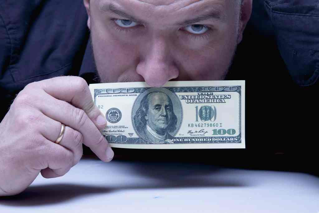 visão de mercado: homem segurando cédula de dólar