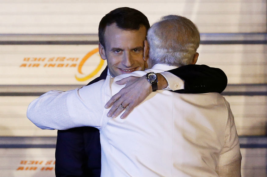 Macron abraçando presidente indiano com sorriso maldoso