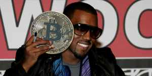 Kanye West segurando uma moeda de bitcoin