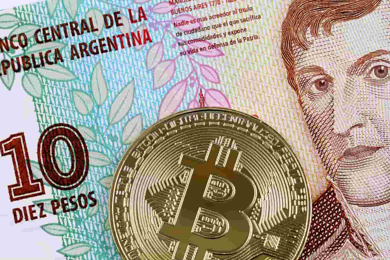 peso argentino com moeda dourada de bitcoin