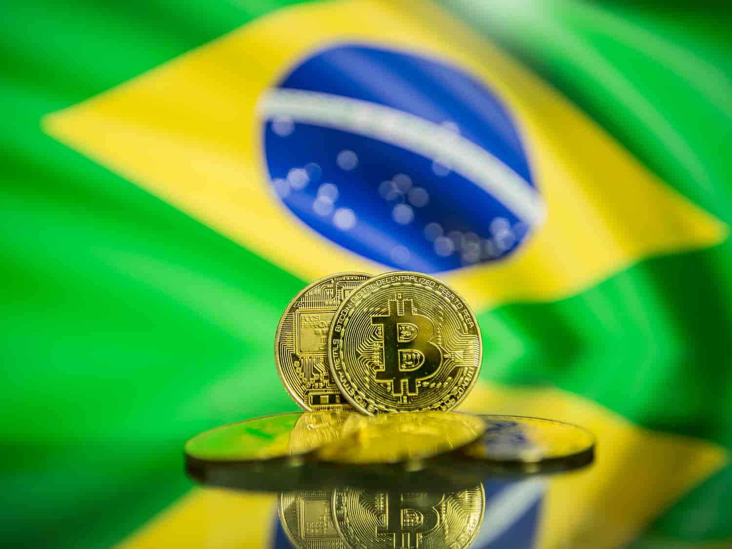 Moeda de Bitcoin com bandeira do Brasil ao fundo
