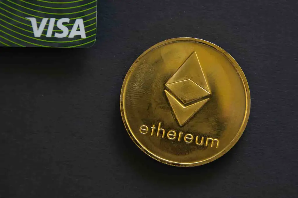 Cartão visa ao lado de moeda do ethereum