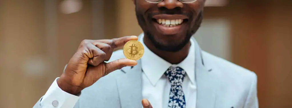 homem segurando moeda de bitcoin