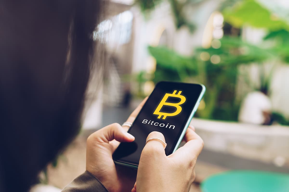 Mulher comprando bitcoin no celular