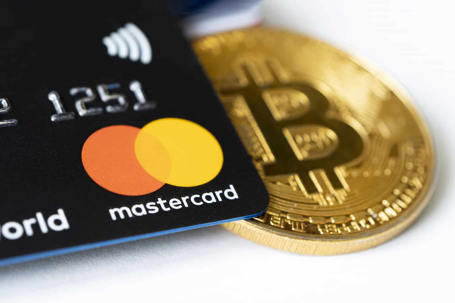 cartão de débito ao lado de moeda do bitcoin