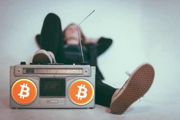 Homem ouvindo podcast com caixas de som com logo do bitcoin