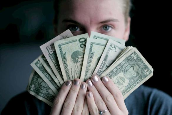 Mulher segurando maço de dinheiro sob o rosto