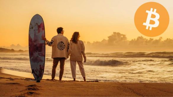 Lorenzo e Maria Fernanda na praia, com prancha de surf olhando o horizonte, com o símbolo do Bitcoin no lugar do sol. - Casal Bitcoiner