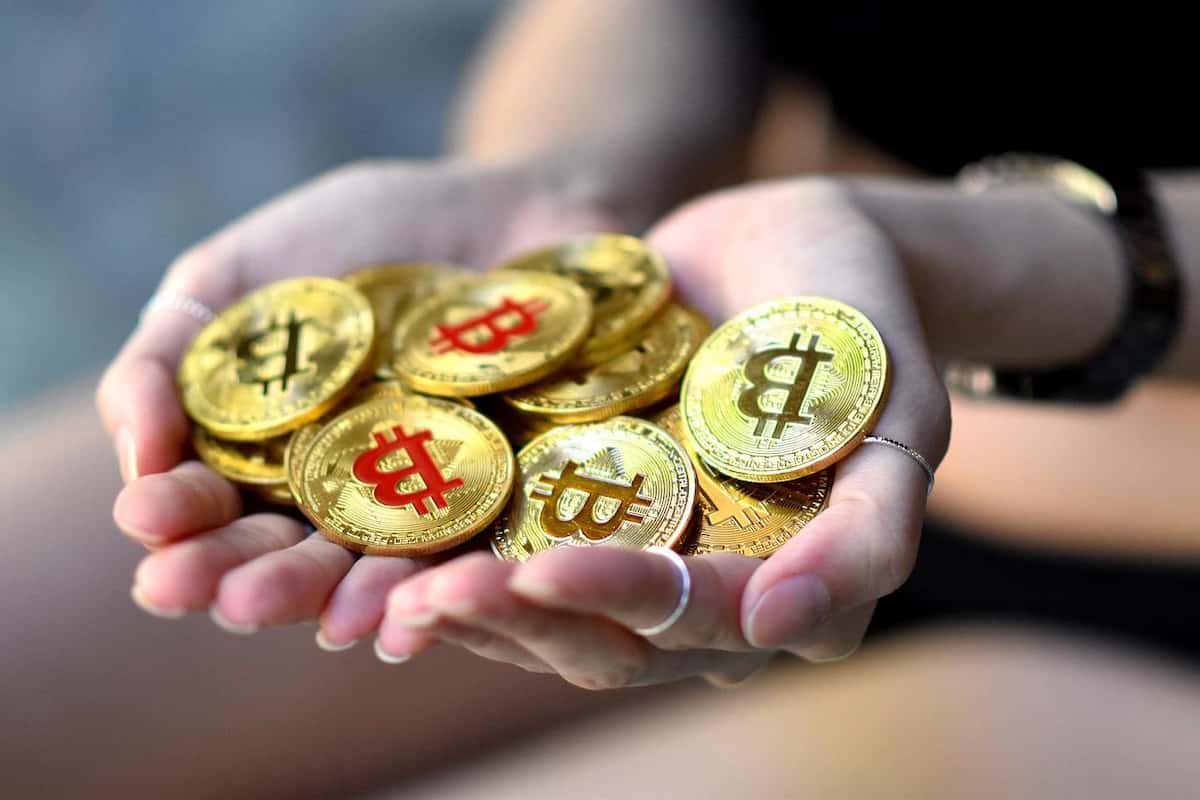 mão segurando moedas de bitcoin