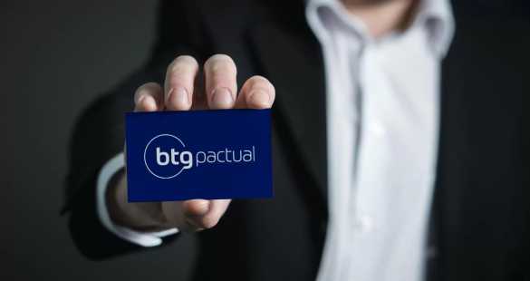 Executivo segurando cartão de visitas do BTG Pactual