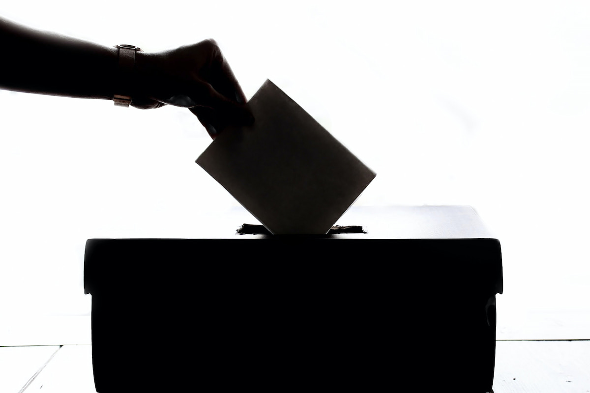 Mão depositando voto em urna