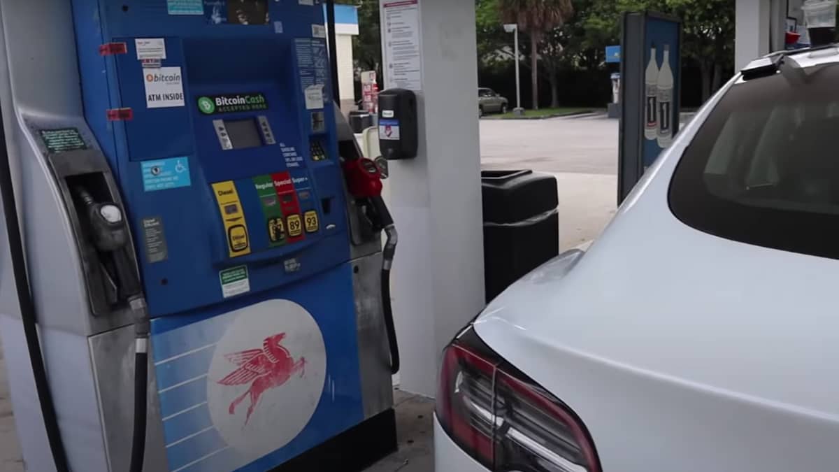 Imagem do vídeo, mostrando o posto de gasolina com adesivos de BTC e Bitcoin Cash