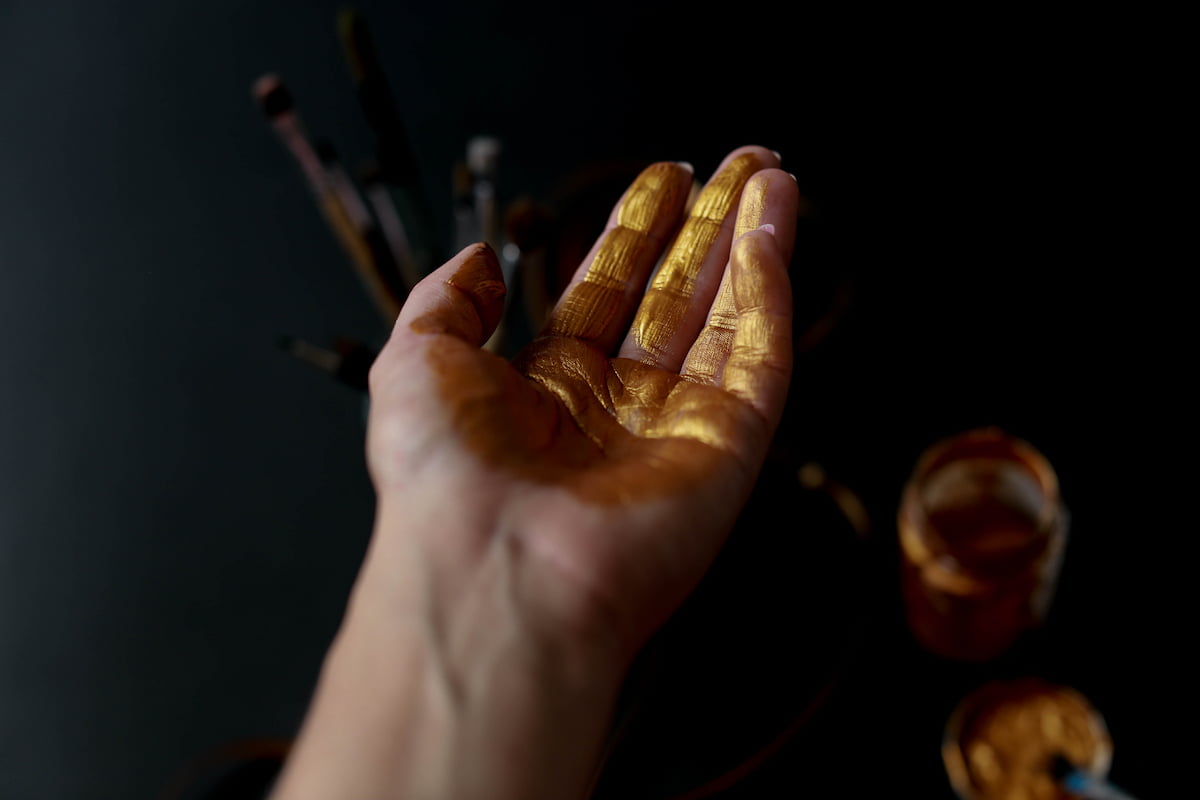Imagem ilustrando manipulação do mercado de ouro - mão pintada de dourado