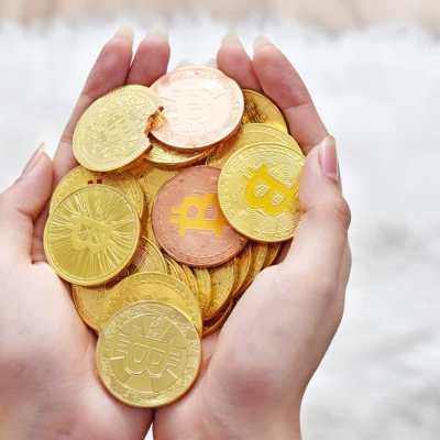 Mão cehio de moedas com bitcoin