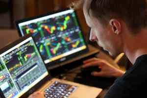 Trader olhando tela do notebook com gráficos de criptomoedas